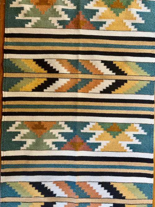 Close-up of Canyon Dusk wool runner showing mustard and clay sunburst medallions on a deep teal ground